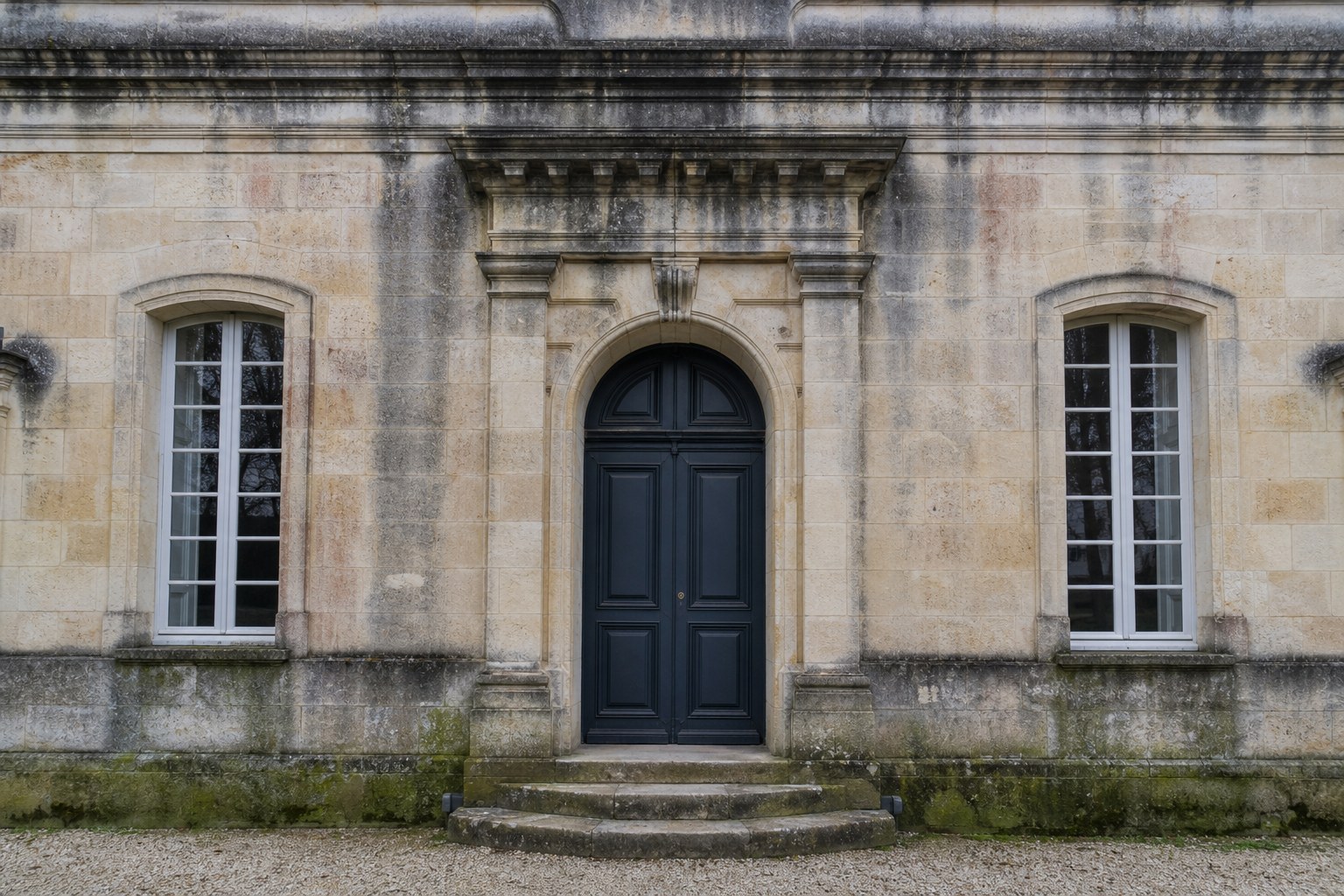 Entrée d’une demeure en pierre avant nettoyage, avec traces noires et mousses